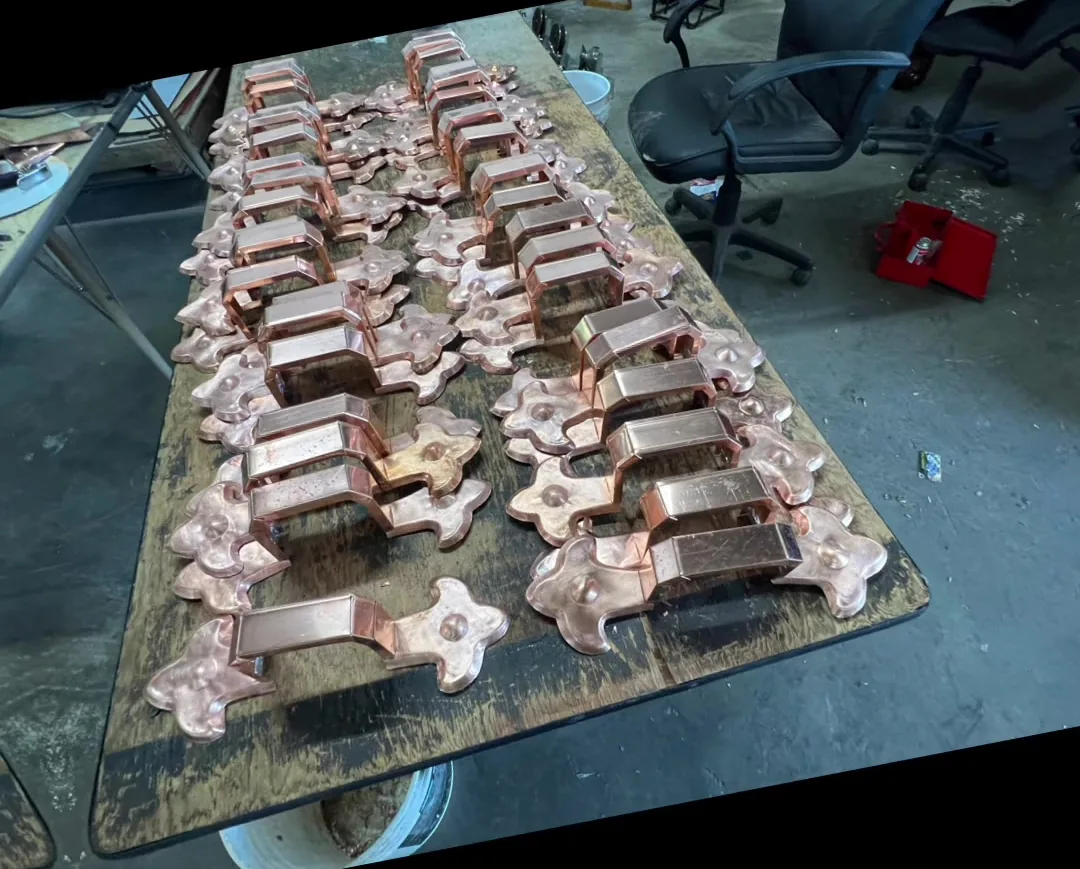 Rows of stamped and formed copper fittings drying on a bench in the shop